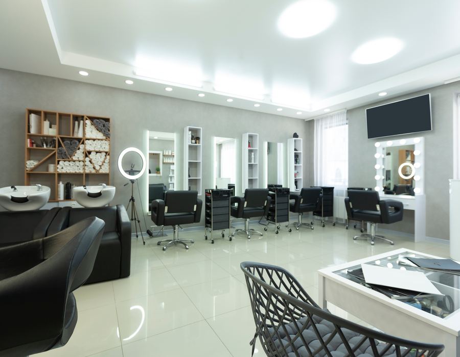 Upscale multi-station salon suite with black chairs, shampoo bowls, and lighted vanity mirrors